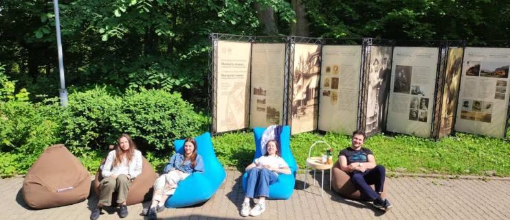 keturi studentai ant sėdmaišių saulėje parke