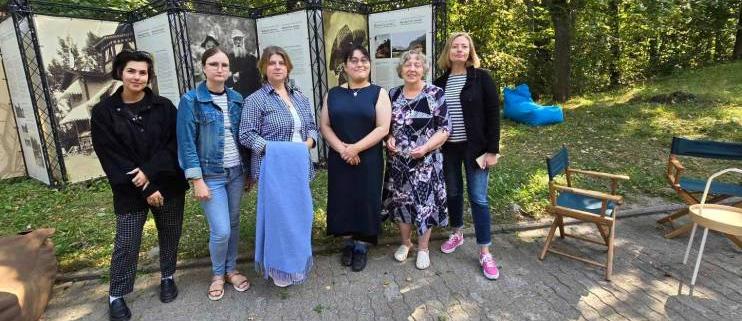 Muziejaus darbuotojai su Aya Kimura muziejaus lauko parodos stendų fone